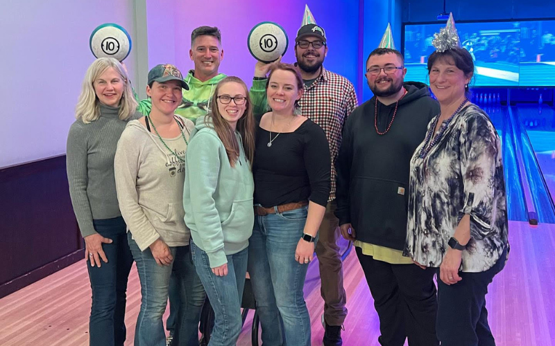 Devine Feed & Pet staff group and posed inside of a bowling alley.